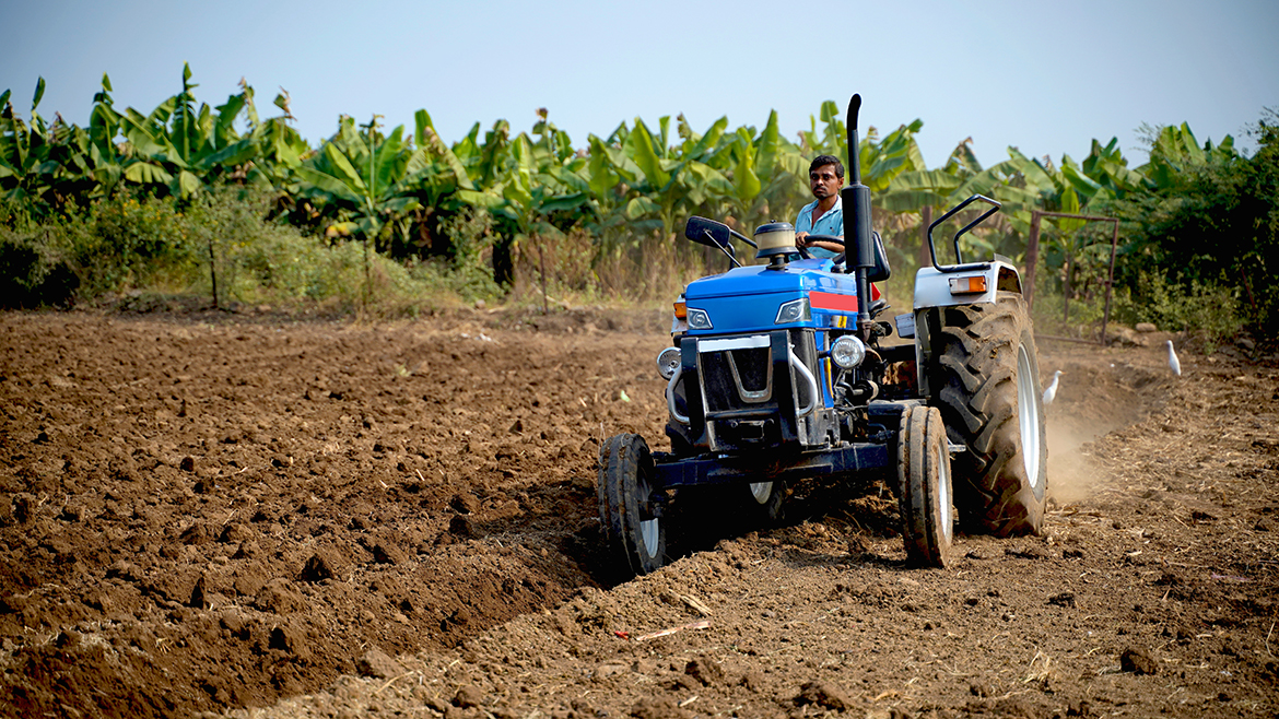 Indian farmer working with tractor in agriculture field.