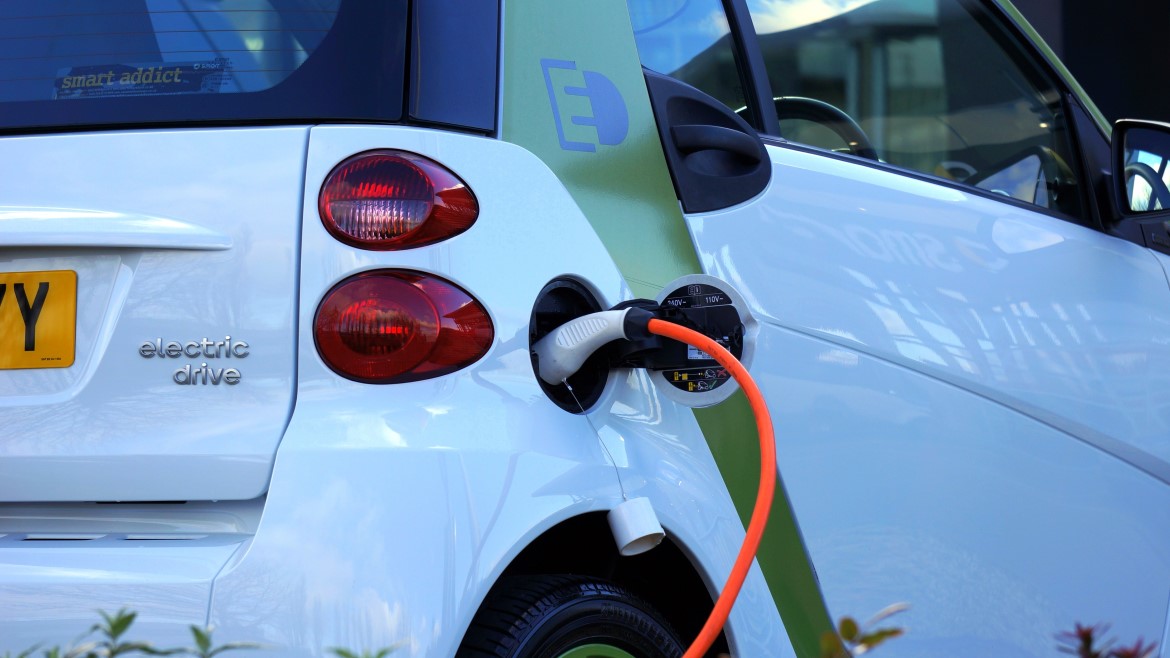 Close view of the side of an electric vehicle with charging unit and orange cord attached