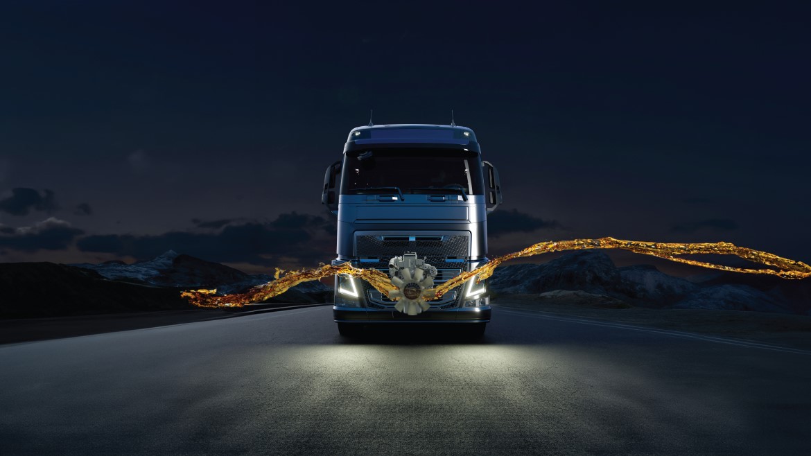 front view of a truck headed toward the camera on a highway at night with a golden light streaming across the landscape