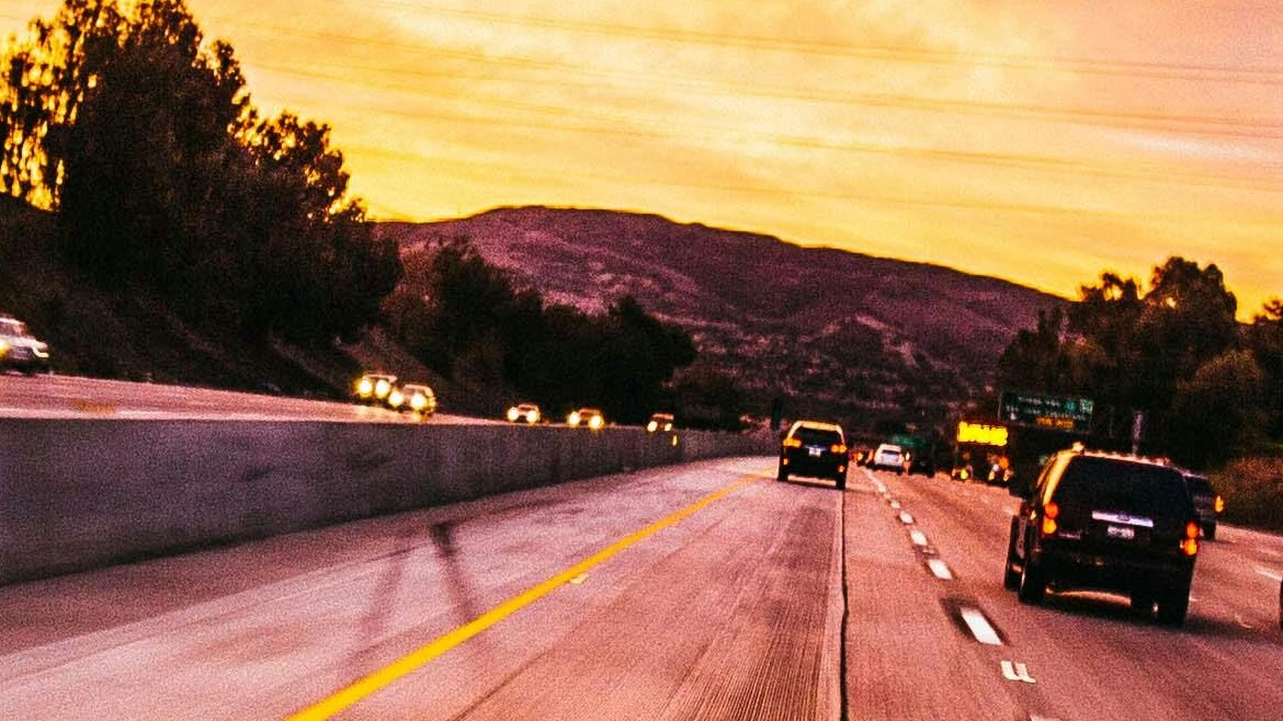 Cars on highway with pink and yellow sky