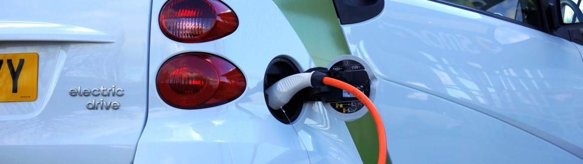 Close view of the side of an electric vehicle with charging unit and orange cord attached