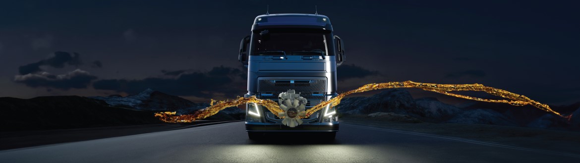 Front view of truck headed toward the camera on a highway at night with a ribbon of gold waving horizontally in front of the truck