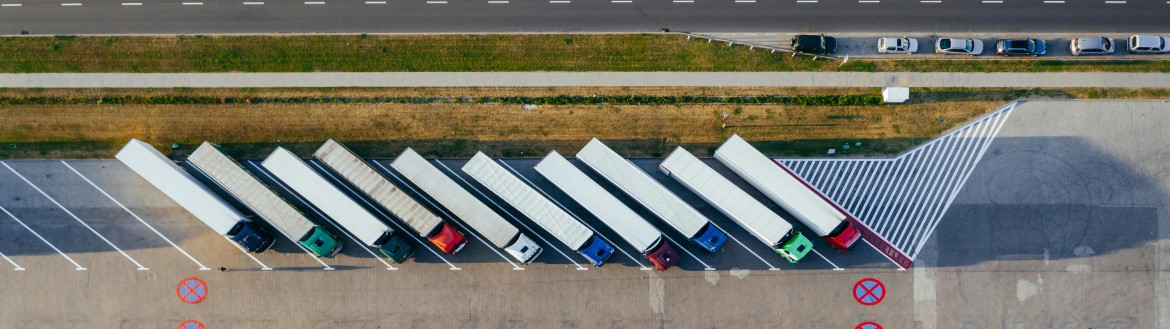 Aerial view of 10 heavy duty trucks parked at an angle in a parking lot