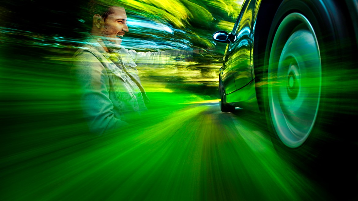 Artistic image with green light streams illuminating a side view of a car on the right and the upper body of someone looking at the car